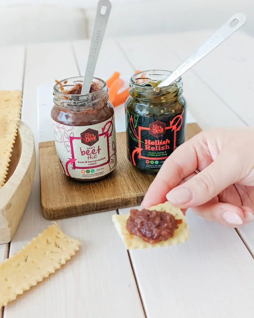 Salsa is piled high on a chip in front of jars of the products giving people a sneak peak at the mix.